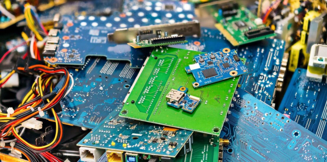 Pile of dismantled electronic circuit boards with colorful wiring and connectors, representing e-waste recycling and recovery.