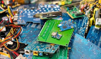 Pile of dismantled electronic circuit boards with colorful wiring and connectors, representing e-waste recycling and recovery.