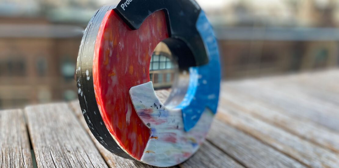 Close-up of ANZRP’s 2023 Product Stewardship Excellence Award with red, white, and blue segments, placed on a wooden surface.
