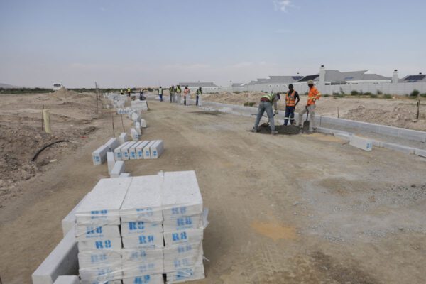 Road construction site in South Africa with workers installing Resin8 concrete curbs and channels, demonstrating practical e‑waste solutions for residential infrastructure.