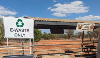 Outdoor e-waste drop-off at Katherine Town Council with ‘E-WASTE ONLY’ sign, metal roof, banner, and clear blue sky.