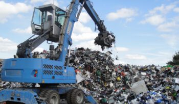Large pile of discarded electronic waste including computers, printers, cables, and plastic components.