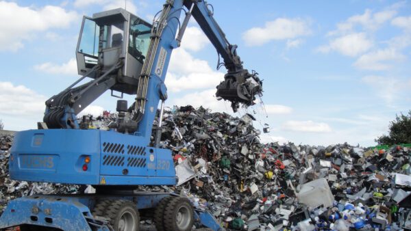 Large pile of discarded electronic waste including computers, printers, cables, and plastic components.