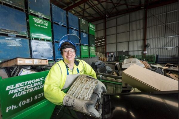 team member recycling Worker handling discarded electronic equipment inside an electronic recycling facility, supporting practical e‑waste solutions for safe sorting and material recovery.